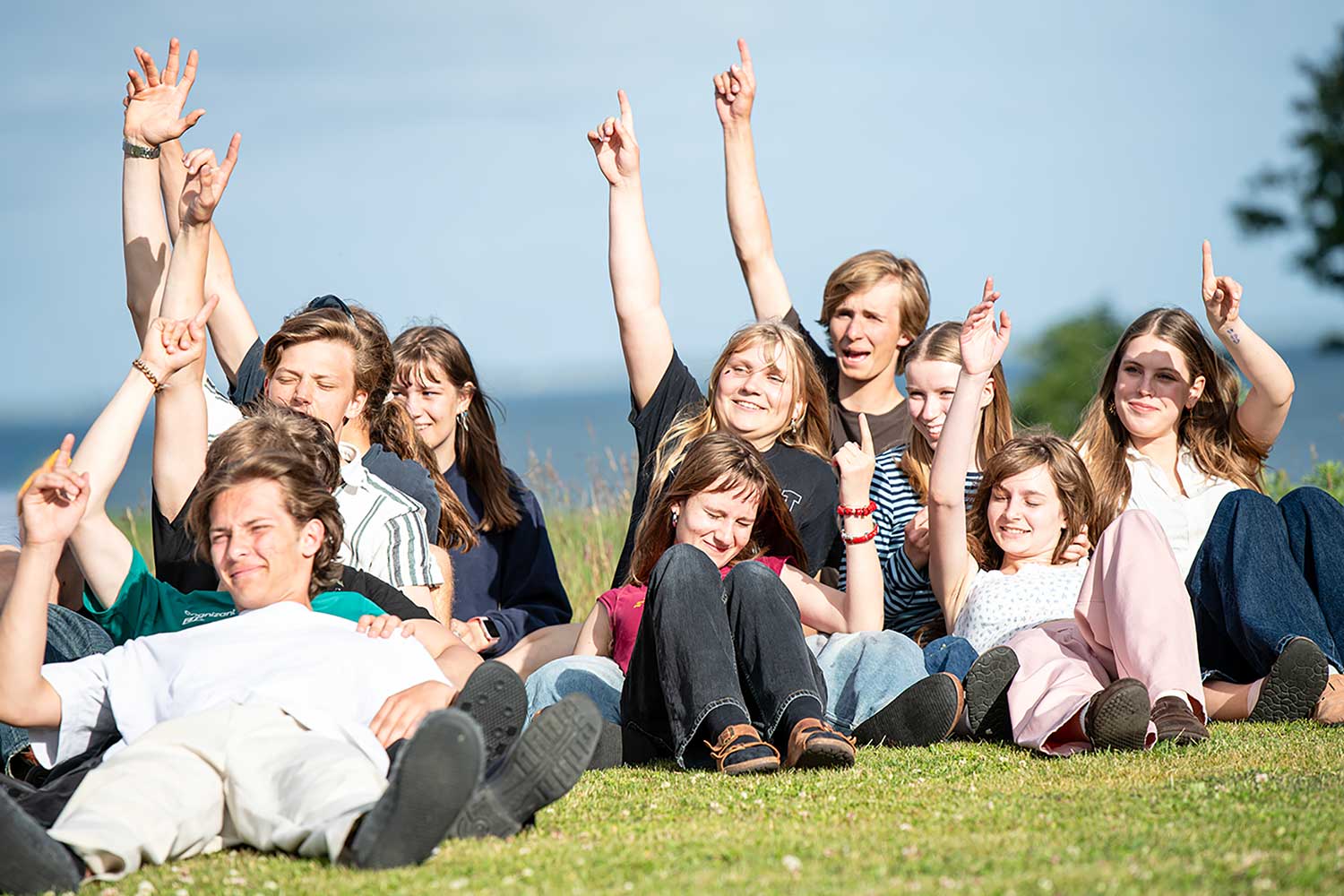 Glade elever nyder fællesskabet på græsset med udsigt over Limfjorden på Venø Efterskole.